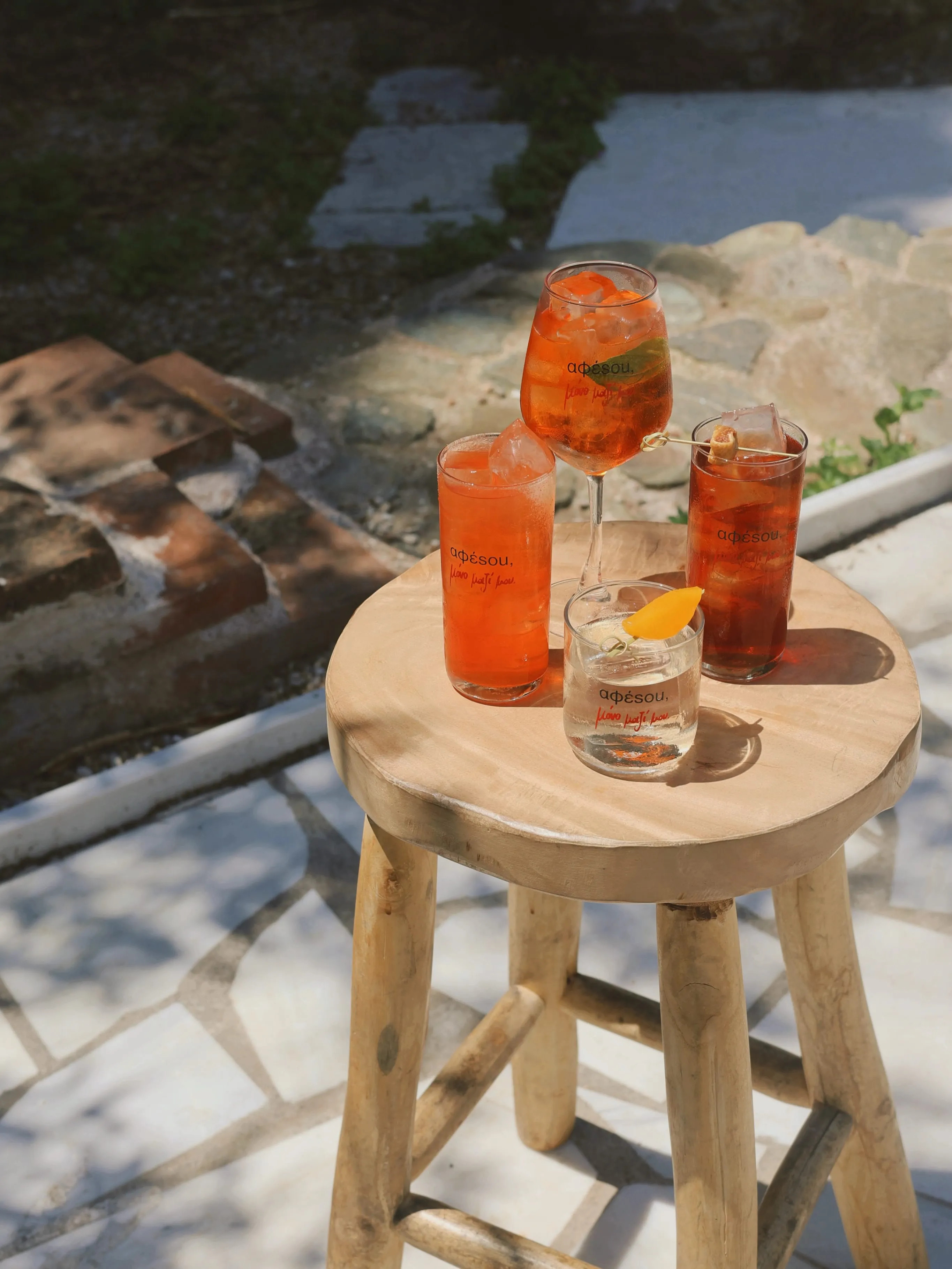 Τέσσερα ποτά Αφέσου σε ξύλινο σκαμπό: spritz, tall drinks και highball σε φως ημέρας